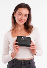 Black leather wallet with a polka dot flap, featuring a metallic accent. Compact rectangular shape, textured material, and embossed logo.