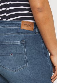 Denimjeans i mörkblått med en mjuk textur. Brun läderetikett med "TOMMY JEANS" på baksidan. Litet logotyp på fickan.
