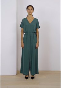 Mono verde de pierna ancha con escote en V y mangas cortas, con cinturilla elástica. Tejido suave de color sólido y sin estampados.