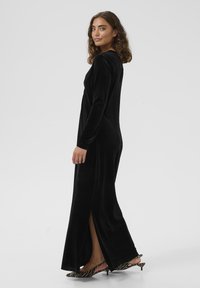 Melna samta maxi kleita ar gariem piedurknēm, sānu izgriezumiem un pieguļošu siluetu, saskan ar zebras raksta papēžiem. Gluda tekstūra un elegants dizains.