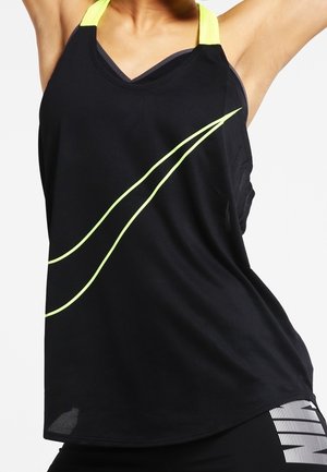 Kobieta nosząca czarny sportowy top bez rękawów z neonowo-żółtymi akcentami oraz czarne legginsy Nike z białym logo.