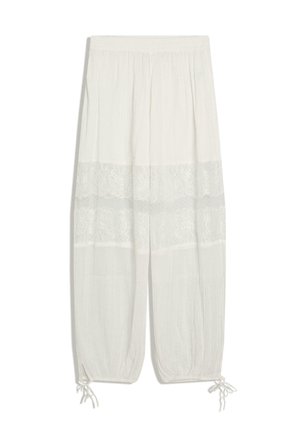 Biele voľné nohavice s elastickým pásom, čipkovaným zdobením okolo stehien a nastaviteľnými šnúrkami na manžetách.