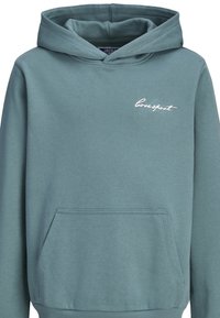 Sweatshirt à capuche en vert bleuâtre discret. Comprend une poche avant, un bord côtelé et un logo brodé blanc "coresport" sur la poitrine. Texture douce.