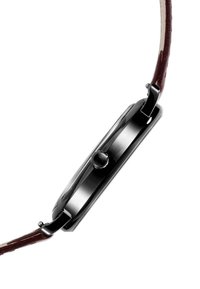 Montre analogique noire avec un boîtier rectangulaire, un bracelet en cuir marron et une couronne sur le côté. Le bracelet présente une finition texturée.