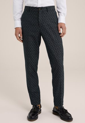 Pantalon à motifs vert foncé avec une coupe slim, doté d'une fermeture à un bouton et de poches arrière. Associé à des mocassins noirs.