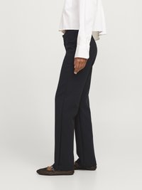 Pantalon bleu marine à coupe droite, avec une texture lisse et une taille mi-haute, associé à des ballerines noires en mesh avec une lanière.