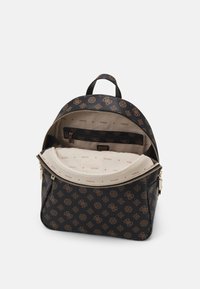Mały plecak Guess w kolorze czarnym i brązowym w wzory, z otwartym suwakiem, odsłaniającym beżową podszewkę i wewnętrzną kieszeń na suwak.