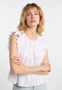 Top bianco senza maniche con dettagli arricciati, caratterizzato da un motivo a righe verticali e pieghe nella zona del busto, realizzato in un tessuto leggero.