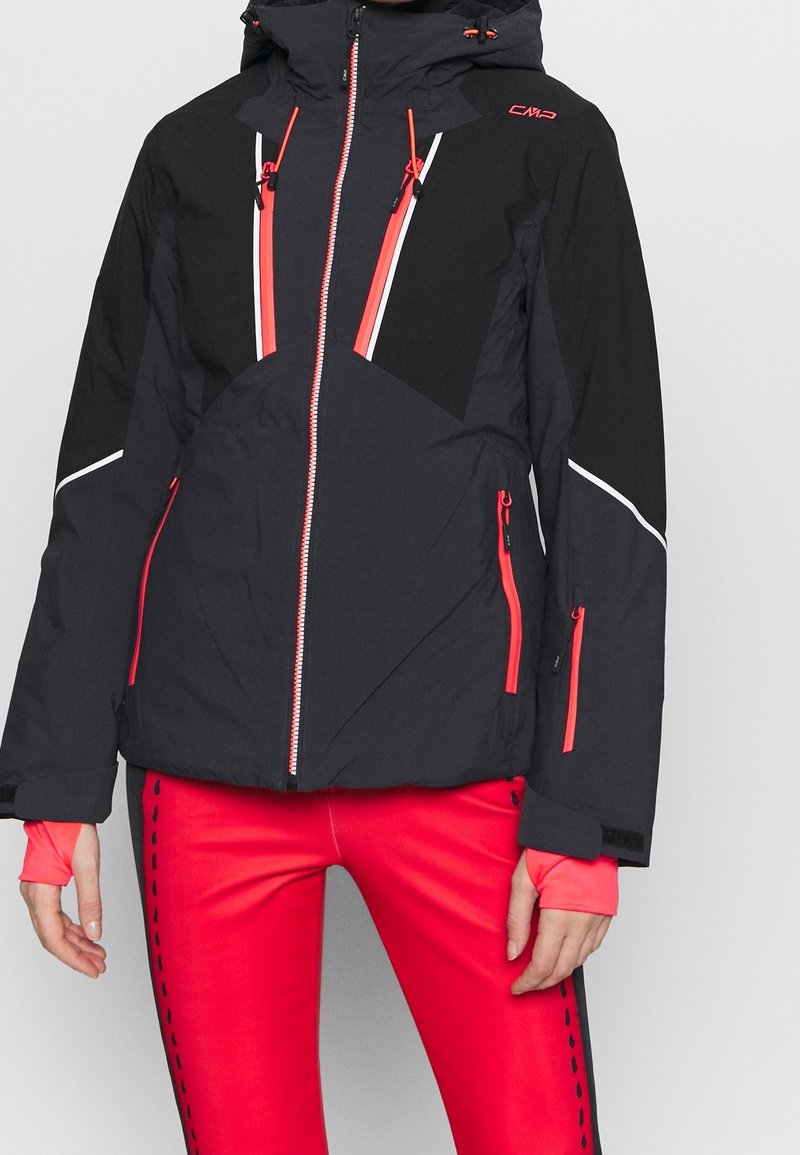 Zwarte skijas met contrasterende rode accenten, ritszakken en een capuchon. Gemaakt van gestructureerd, geïsoleerd materiaal voor warmte.