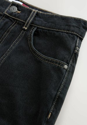 Jeans in denim scuro con tasca frontale, cuciture a contrasto e chiusura con bottone metallico. Texture liscia e design affusolato.