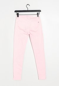Vaqueros ajustados de algodón en color rosa claro, con una textura suave, diseño de cinco bolsillos y costuras blancas en los bolsillos.
