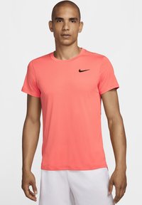 Rožinė Nike sportinė marškinė turi tekstūruotą, kvėpuojančią medžiagą, trumpas rankoves, apvalų kaklą ir subtilų juodą logotipą ant krūtinės.