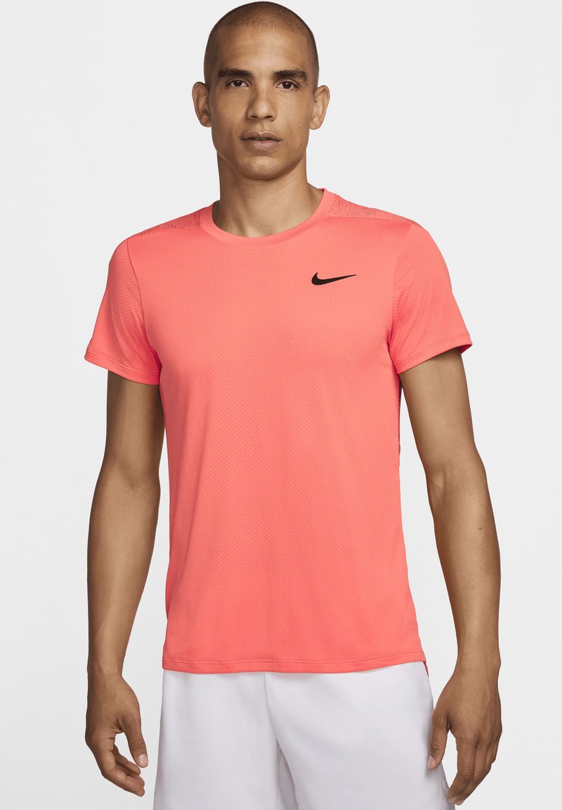 Rožinė Nike sportinė marškinė turi tekstūruotą, kvėpuojančią medžiagą, trumpas rankoves, apvalų kaklą ir subtilų juodą logotipą ant krūtinės.