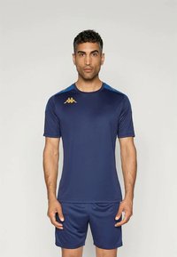 Tumesinine spordisärk lühikeste varrukatega ja helesiniste aktsentidega. Omab siledat tekstuuri ja kuldset logo vasakul rinnal.