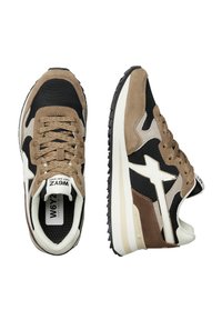 Baskets de sport marron et noires avec des matériaux en maille et en daim, dotées d'une semelle couleur crème, d'une semelle extérieure noire et d'accents blancs.