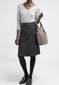 Wełniany sweter w kolorze jasnoszarym z dekoltem w serek; czarna skórzana spódnica w kształcie litery A; szara torebka; czarne rajstopy; czarne buty typu slip-on.
