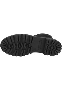 Suela de bota de goma negra con patrones de surcos profundos, que cuenta con tacos de tracción pronunciados y una zona central lisa para mejor agarre.