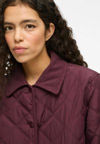 Quilted bordeaux jack met een ribbelkraag en knoopsluiting, uitgerust met diamante patronen. Zachte textuur en een relaxte pasvorm.