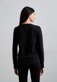 Zwarte lange mouwen shirt met een ronde hals en een zachte textuur. Eenvoudig ontwerp, aansluitende silhouet en geen zichtbare patronen of hardware-details.