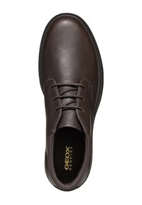 Scarpa in pelle marrone con punta arrotondata, design con lacci, superficie testurizzata e suola in gomma nera. Logo dorato visibile all'interno.