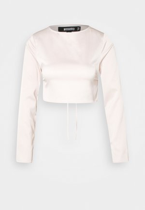 Haut court à manches longues de couleur rose clair en tissu lisse. Il présente un col rond et un détail de nouage à l'avant de l'ourlet. Étiquette de la marque visible à l'intérieur.