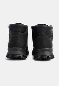 Botas de senderismo negras con parte superior texturizada, cuello acolchado, talón reforzado y suela resistente con profundas tracciones para mejorar la adherencia.