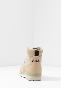 Sneaker alta beige con tomaia in suede e mesh, collare imbottito, inserto sul tallone in nero a contrasto e dettaglio del logo in rosso e nero.