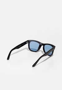 Ochelari de soare din plastic negru cu lentile albastre, design cu ramă pătrată și brațe elegante. Prezintă o marcă subtilă pe lateral.