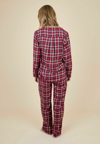 Punane ja roheline ruuduline pidžaama komplekt pikkade varrukatega ja pükstega, millel on mugav lõige ja pehme kangastekstuuri, vaadatuna tagant.