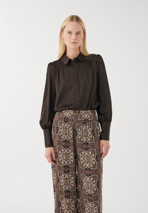 Dark brown silky blouse with a collar and button closure, paired with patterned brown pants featuring beige designs and an elastic waistband.