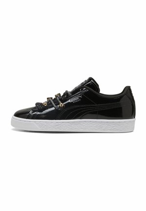 Lage zwarte sneakers van lakleer met witte gestructureerde zool, zwarte veters en gouden veteroogjes, zijbranding op een effen witte achtergrond.