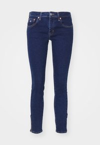 Jeans ajustados de denim azul oscuro con un diseño limpio, que cuentan con bolsillos delanteros y traseros, y acentos de costura clara.