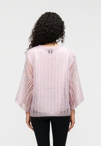 Ροζ ανοιχτόχρωμο πλεκτό πουλόβερ με φαρδιά μανίκια, ανοιχτό σχέδιο πλέξης και στρογγυλή λαιμόκοψη, με μικρό λογότυπο στο πίσω μέρος.