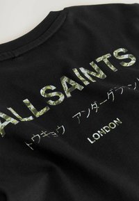 Juodas medvilnės marškinėliai su užrašu "ALLSAINTS" ir "LONDON" žalių lapų raštu, papildomu tekstu japonų kalba žemiau.