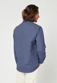 Donkerblauwe gestreepte shirt met een puntige kraag en knoopmanchetten, met een relaxte pasvorm en afgeronde zoom, gemaakt van lichtgewicht stof.