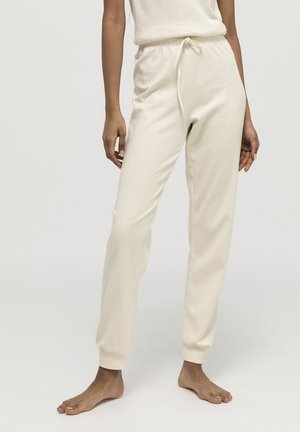 Joggers de color crema claro, hechos de una tela suave, con una cintura elástica y cordón ajustable, y puños acanalados en los tobillos.