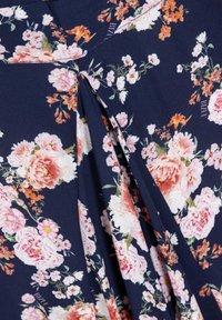 Materiał z kwiatowym wzorem w granatowym kolorze, ozdobiony różowymi i pomarańczowymi kwiatami. Tkanina ma miękką teksturę z plisowanymi detalami.