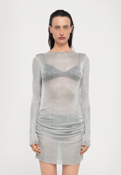 Doorzichtig zilveren lange mouw jurk met een figuurvormend lijfje, geplooide textuur bij de taille en een lichte ronde halslijn. Transparante stof toont de onderkleding.