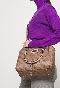 Brązowa torebka w wzory o kształcie strukturalnym, z metalowymi akcentami i różowymi uchwytami. Gładka tekstura z dekoracyjnym detalem w formie łańcucha.