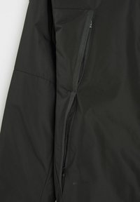 Czarna kurtka o gładkim, matowym wykończeniu. Zawiera zasuwaną kieszeń na górnej lewej rękawie oraz subtelne detale z logo.