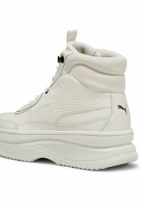 White high-top sneakers made of textured leather, featuring a thick sole, side logo, and lace-up front with a heel tab.