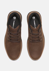 Zapatos de cuero marrón con diseño de cordones, suela de un tono claro en contraste y logotipo de Timberland en la lengüeta. Presenta forro de tejido texturizado.