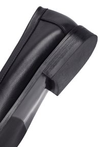 Close-up van de hak van een zwarte leren schoen met rubberen zool en gestructureerde grip aan de onderzijde.