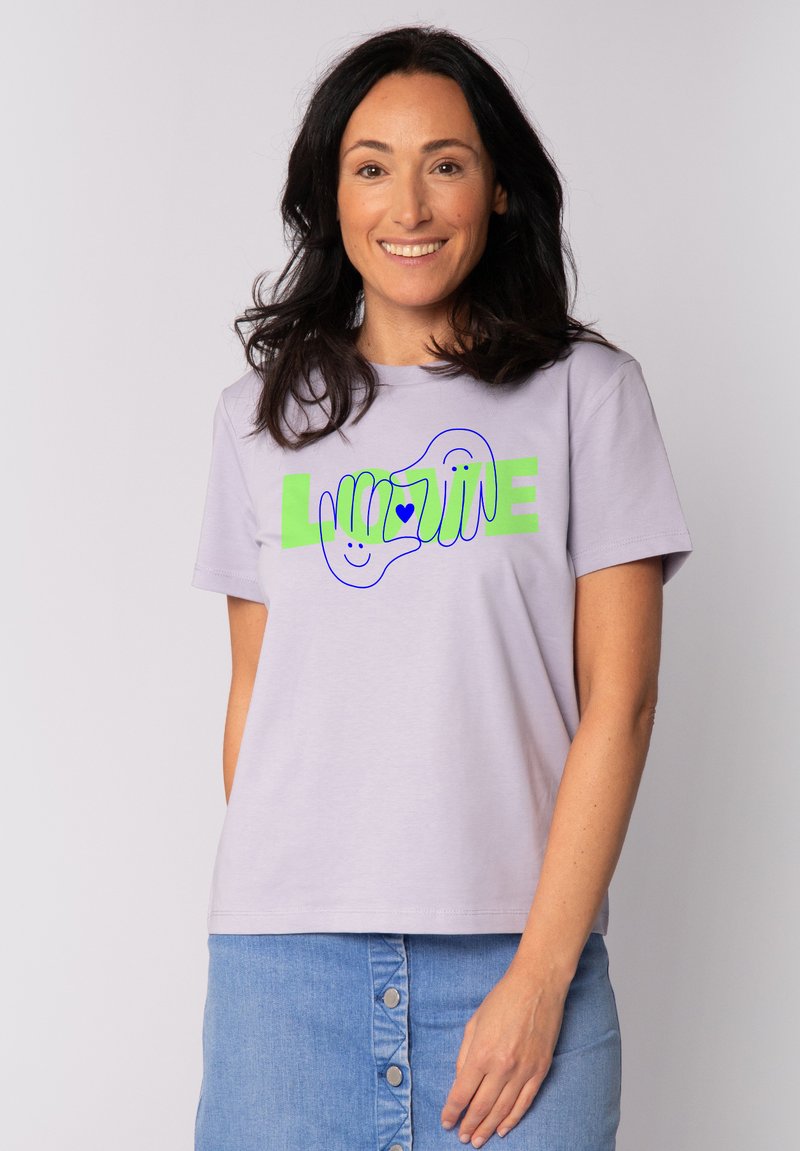 T-shirt en coton lilas à manches courtes, avec un graphique vert et bleu de mains et le mot "LOVE" sur la poitrine.