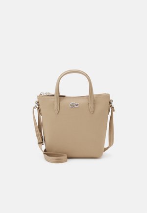 Sac à main beige en matériau synthétique texturé, doté d'une fermeture éclair supérieure, de deux poignées et d'une bandoulière amovible. Accent logo présent.