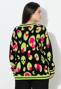 Schwarzer Pullover mit einem gewagten Muster aus pinken und limettengrünen Totenköpfen und Formen, mit gerippten Bündchen und Saum. Strickstruktur, oversized Schnitt.