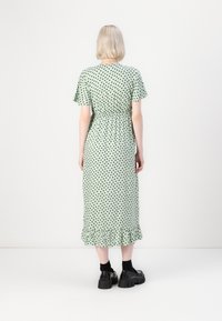 Roheline midi kleit mustade südameprintidega, lühikesed rükeldavad varrukad, elastne vöökoht ja laineline hem. Kandmine mustade platvormkingadega.