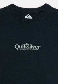 T-shirt preta de gola redonda com o logótipo da Quiksilver centrado e o texto "The Original Surf Co Since 1969" em cinza claro no peito.