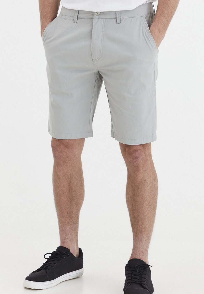 Grå chinoshorts med flat front, sidelommer og pene sømmer, kombinert med svarte sneakers. Uformell design med lett stoff.
