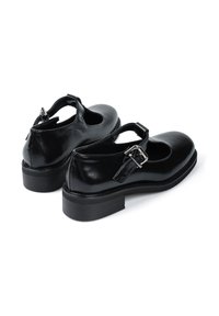 Czarne skórzane buty typu Mary Jane z okrągłym noskiem, paskiem na kostkę z klamrą oraz niskim obcasem słupkowym. Gładka faktura i minimalistyczny design.